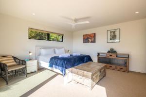 a bedroom with a bed and a table and a chair at Hekerua Heights with Hot Tub and Seaviews in Oneroa +16 photos