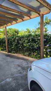 a white car parked under a wooden pergola at Casa Goiaba in Piçarras