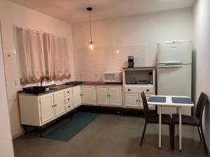 a kitchen with white cabinets and a table and a refrigerator at Casa Goiaba in Piçarras