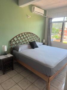 a bedroom with a bed and a window with a fan at Casa Dreamy in Zihuatanejo