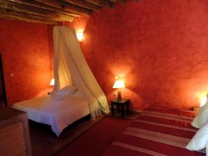 a bedroom with a bed with a mosquito net at Dar Qamar in Agdz