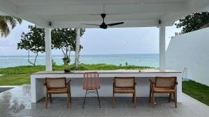 a bar with four chairs and a view of the ocean at Adams Villas in Katiet