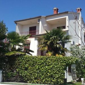 a white house with palm trees in front of it at Apartments Luce in Rovinj