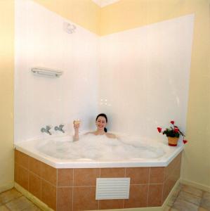 a woman is sitting in a bath tub at Elliotts Kapiti Coast Motor Lodge in Paraparaumu Beach