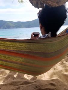 a person sitting in a hammock with a cell phone at Bio Coliving Tayrona, Eco Retreat for You or Your group with Fast, Reliable WiFi & Power in Nature in Santa Marta