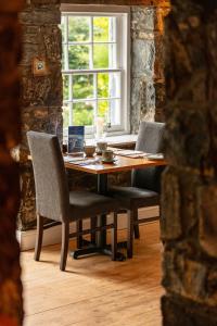 a dining room table with two chairs and a window at Eddrachilles Hotel in Scourie