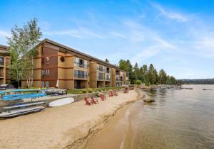 a beach with chairs and a building next to the water at Lakeside Getaway Beach Access Shared Pool and Grills in McCall