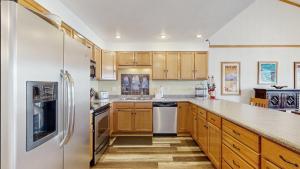 a kitchen with wooden cabinets and a stainless steel refrigerator at Lakeside Getaway Beach Access Shared Pool and Grills in McCall