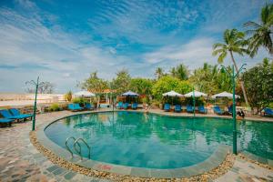 a swimming pool at a resort with palm trees at Le Aqua Resort & Spa Phan Thiet - Swiss Village Resort & Spa in Mui Ne