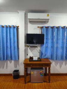 a room with a desk and a blue curtain at Old City Guest House in Sukhothai