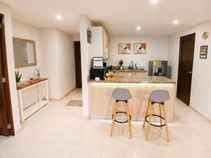 a kitchen with two bar stools and a counter top at Apto Deluxe, 3 hab, piscina y rooftop en Escalón in San Salvador +45 photos
