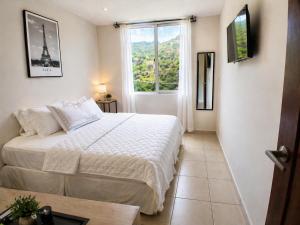 a bedroom with a white bed and a window at Apto Deluxe, 3 hab, piscina y rooftop en Escalón in San Salvador