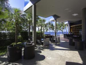 een restaurant met uitzicht op de oceaan en palmbomen bij Kalm Bangsaen Hotel in Bangsaen