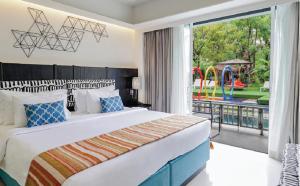 a bedroom with a bed and a view of a playground at Sugar Marina Hotel - ART - Karon Beach in Karon Beach