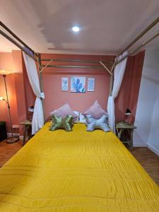 a bedroom with a large yellow bed with two pillows at Papa house red room in Pak Kret