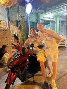 two men are standing next to a motorcycle at Papa house red room in Pak Kret