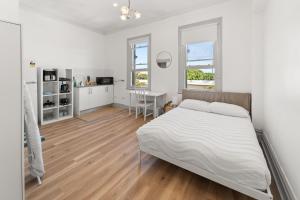 a white bedroom with a bed and a kitchen at Olympic Paddington Budget Hotel - across Allianz Stadium in Sydney