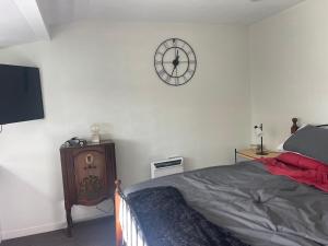 a bedroom with a bed and a clock on the wall at Kaiapoi Village Le Shack in Kaiapoi +1 photo