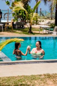 two women sitting in a swimming pool at Nikara Beach Villas Arugambay in Arugam Bay
