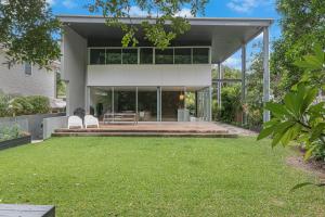 a house with two white chairs on a lawn at Dune Ten in Fingal Head