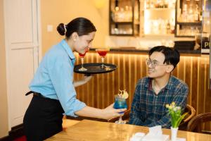 a woman holding a tray with a woman holding a drink at Kailash Boutique Hotel in Kathmandu