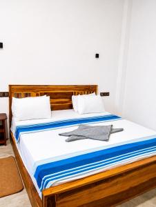a bedroom with a wooden bed with blue and white sheets at New Happy bay in Arugam Bay