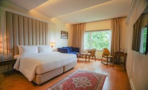 a bedroom with a large white bed and a desk at Sarovar Premiere Srinagar in Srinagar +50 photos