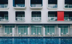 a building with tables and chairs next to a pool at Sugar Marina Hotel - NAUTICAL - Kata Beach in Kata Beach