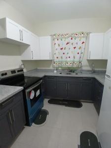 a kitchen with a stove and a curtain in it at The Cosy Home in Lucea