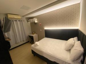 a bedroom with a bed with a light on the wall at Smart Hotel Joinville in Joinville