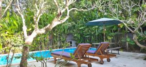 a patio with chairs and an umbrella next to a pool at The Forty Eight Resort Candidasa in Candidasa