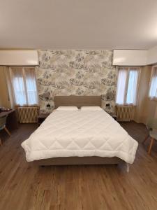 a bedroom with a large white bed with a wall at Hotel Emiliana in Villadossola