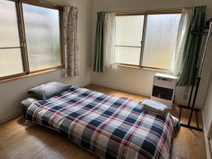ein Schlafzimmer mit einem Bett und zwei Fenstern in der Unterkunft TomoHouse in Kutchan