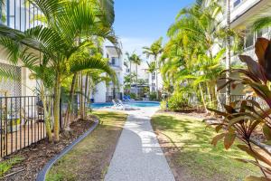 un chemin bordé de palmiers devant un bâtiment dans l'établissement Beachside Mooloolaba, à Mooloolaba
