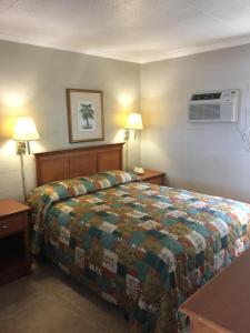 ein Hotelzimmer mit einem Bett und zwei Nachttischen in der Unterkunft Campbell Motel in Cocoa