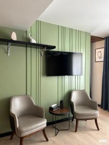 a living room with two chairs and a flat screen tv at Empire City in Karagandy