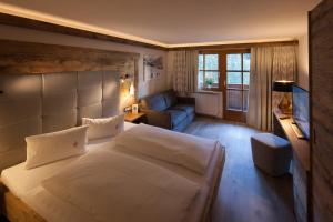 a bedroom with a large white bed and a couch at Das alpine Lifestyle Berghotel Madlener in Damuls