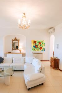 a living room with white furniture and a chandelier at Villa Marecoco in Forio d'Ischia