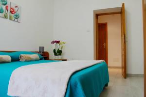 een slaapkamer met een bed met een blauwe en witte deken bij B&B Le Orchidee in Alghero