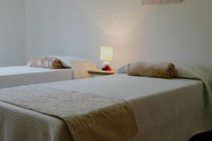 アルゲーロにあるB&B Le Orchideeのベッドルーム1室(ベッド2台、ランプ付きテーブル付)
