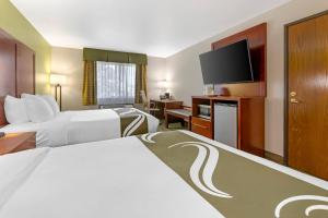 a hotel room with two beds and a flat screen tv at Quality Inn & Suites Stoughton - Madison South in Stoughton