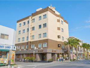 a large building on a city street with palm trees at Ishigakijima Hotel Cucule in Ishigaki Island