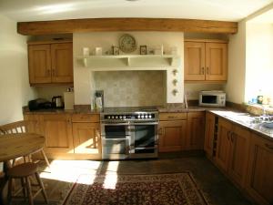 a kitchen with wooden cabinets and a stove top oven at Scarr House Farm in Muker +18 photos