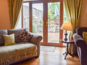 a living room with a couch and a glass door at Scarr House Farm in Muker