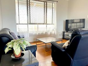 a living room with two chairs and a tv at 14A Convenient Ensuite Room in Coopers Plains in Brisbane