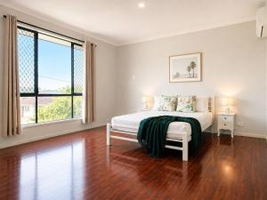 a white bedroom with a bed and a large window at 14A Convenient Ensuite Room in Coopers Plains in Brisbane