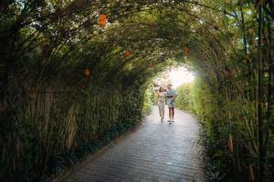 a man and woman walking through a bamboo tunnel at Kaamala Resort & Spa Ubud by Ini Vie Hospitality in Ubud