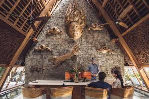 a man standing in front of a wall with a head on it at Kaamala Resort & Spa Ubud by Ini Vie Hospitality in Ubud