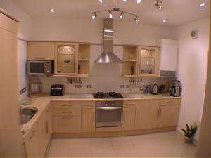 a kitchen with wooden cabinets and a stove top oven at Earle House Serviced Apartments in Crewe