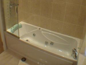 a white bath tub in a bathroom with a shower at Earle House Serviced Apartments in Crewe +22 photos